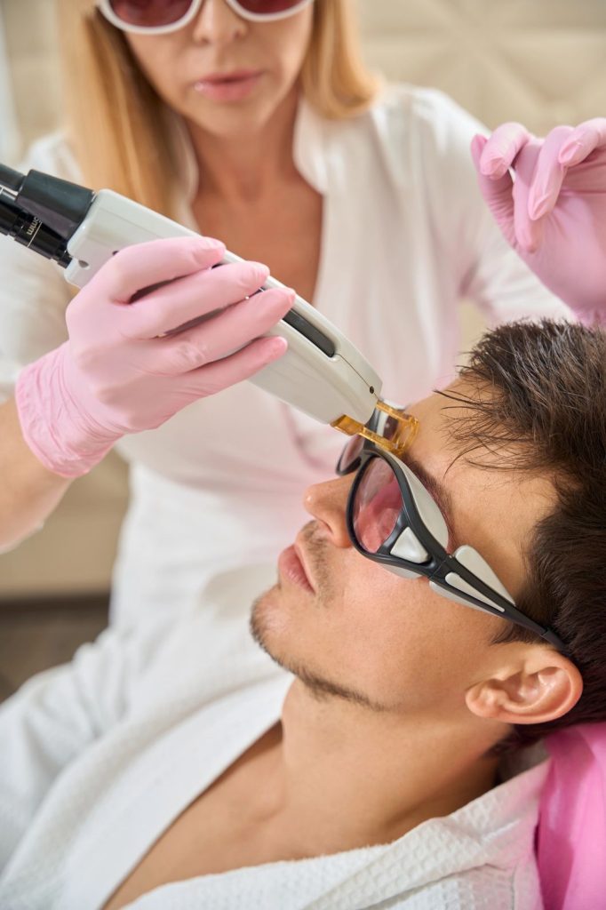 Professional using laser on forehead, ideal for laser hair removal school San Antonio training.