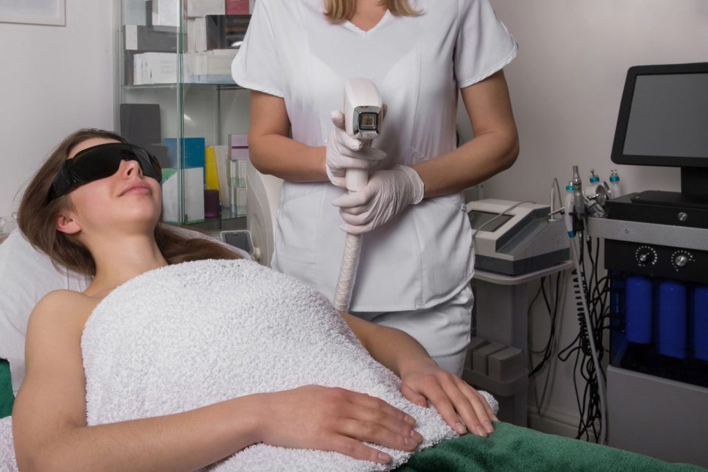 Laser hair removal technician training San Antonio covers IPL use on abdomen. Trainee performs treatment in modern spa.