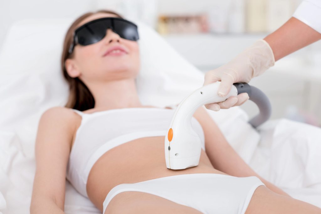 Client receiving safe bikini line laser hair removal by certified practitioner using protective eyewear, following laser safety certification standards.