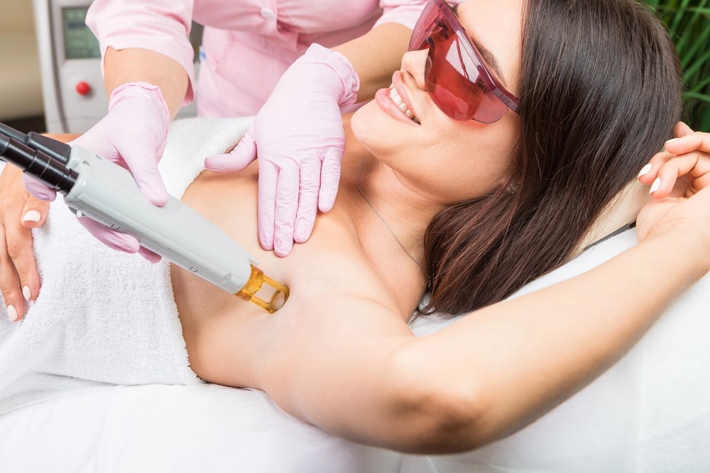 Laser hair removal school San Antonio practice session showing underarm laser treatment with pink uniformed instructor in spa clinic.