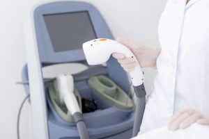 Professional technician handling advanced laser equipment for hair removal, adhering to laser safety certification guidelines in a clinical setting.