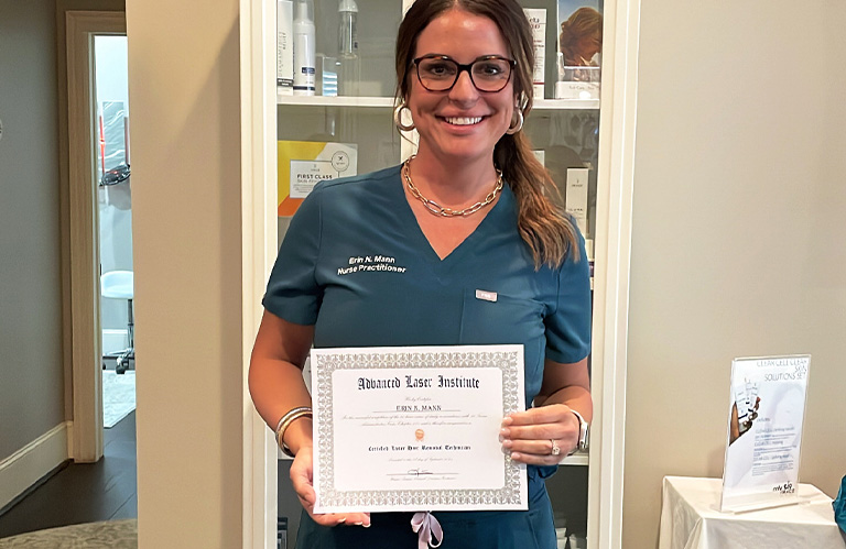 A proud graduate holding her official laser hair removal technician certification woodlands approved certificate.