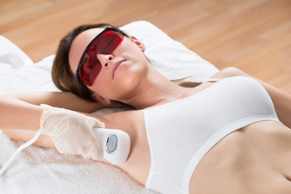 Patient wearing safety goggles during underarm treatment at a laser hair removal certification training facility.