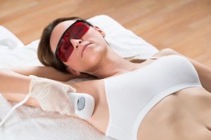Patient wearing safety goggles during underarm treatment at a laser hair removal certification training facility.