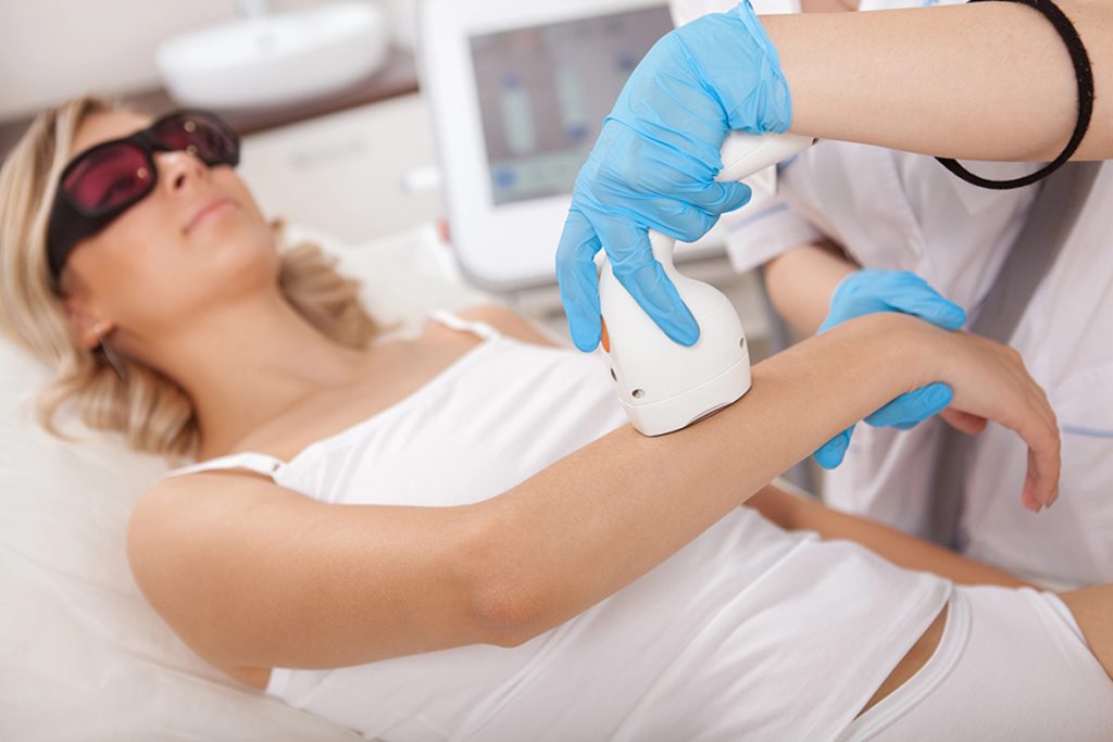 Learn hair removal at a certified laser technician school near me Woodlands; student treats a patient's arm.