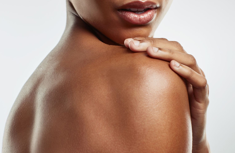 A close-up of a woman's smooth, clear shoulder after completing a full course of treatments at a professional laser hair removal academy.
