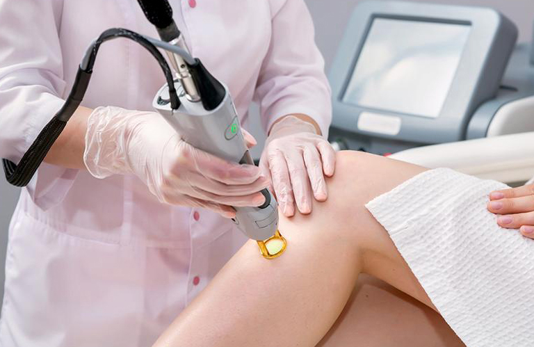Detailed view of a technician using a medical-grade laser handpiece for a precision leg treatment at a laser technician school woodlands.