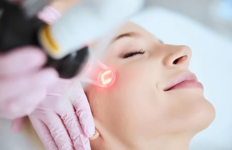 A student performing a precise facial laser treatment using advanced medical equipment as part of their best laser hair removal education.