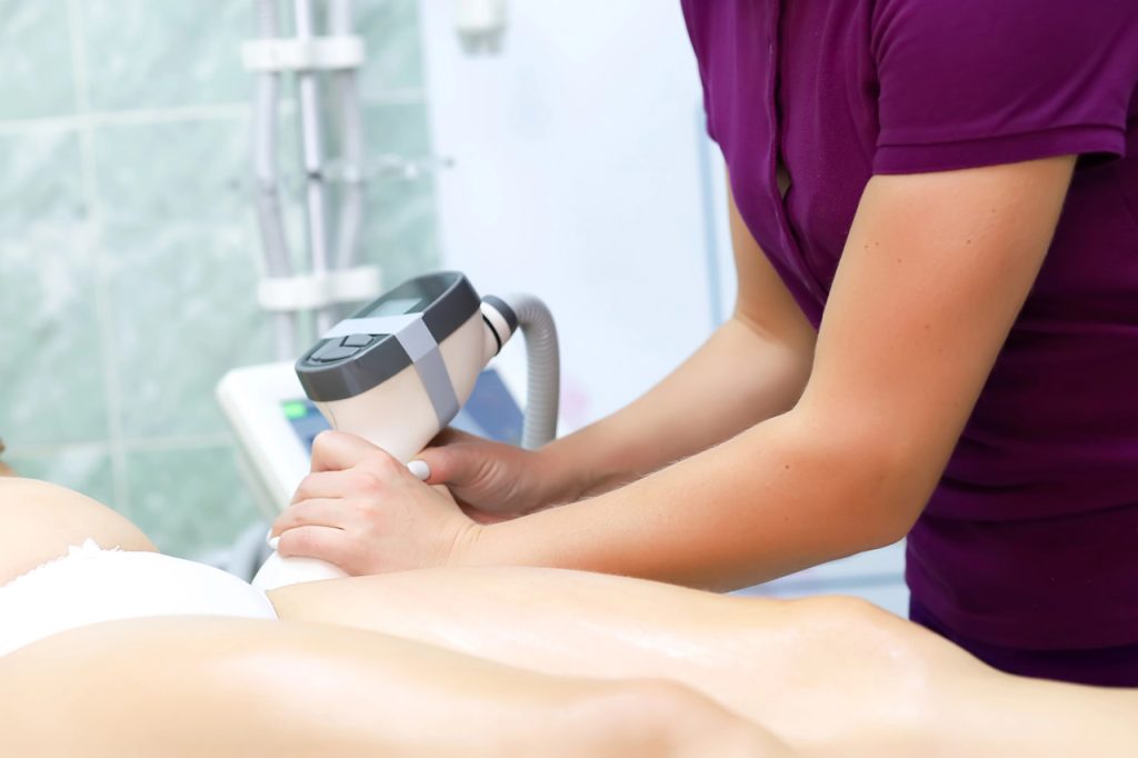 Professional technician performing leg treatment for laser hair removal certification in a modern medical clinic.