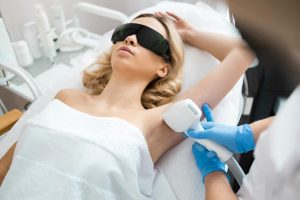 A technician treats a patient's underarm, providing visual aid for laser hair removal education content.