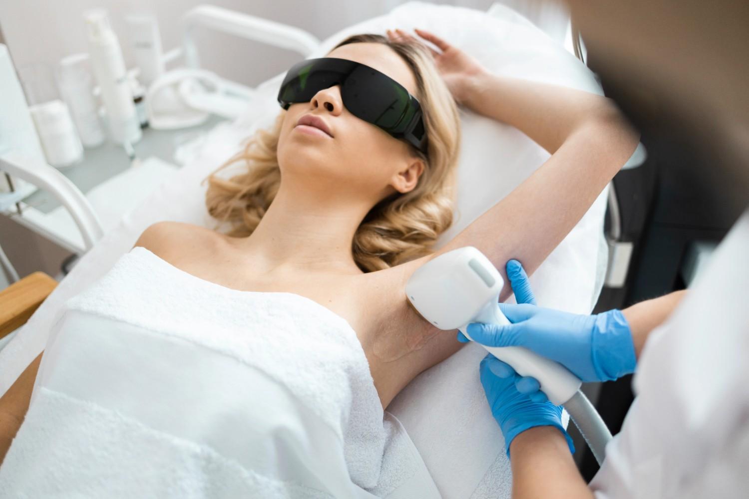 A technician treats a patient's underarm, providing visual aid for laser hair removal education content.