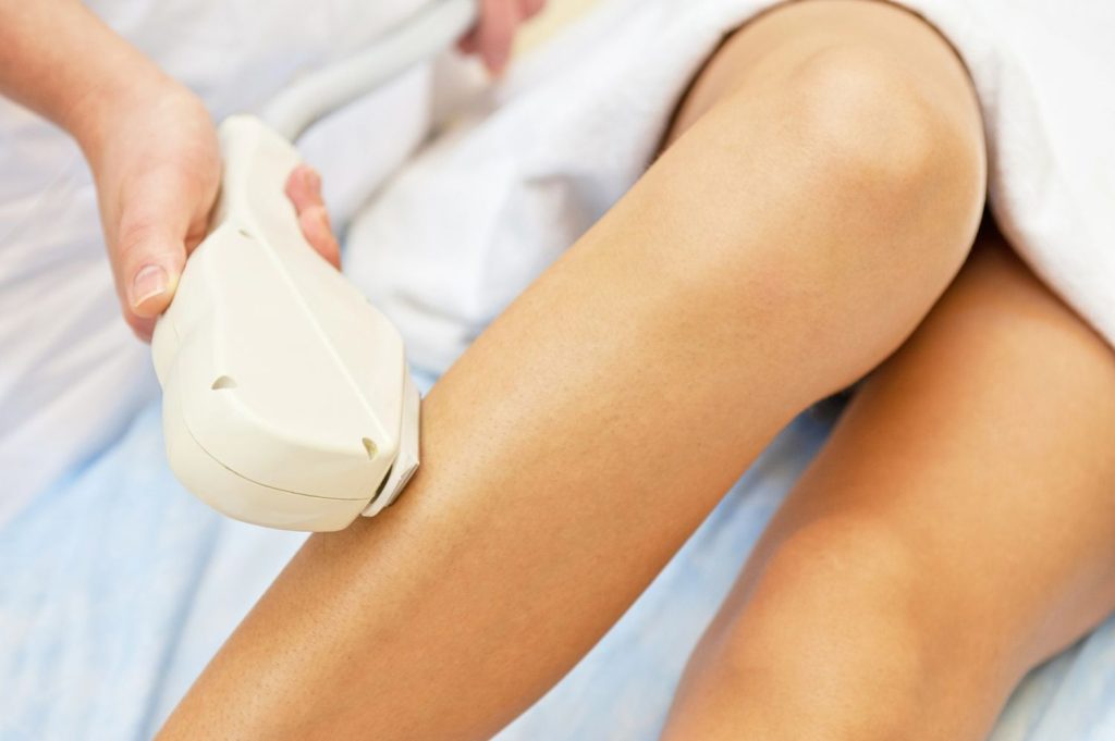 A student in laser hair removal technician training Woodlands performs a precise lower leg hair removal procedure. 