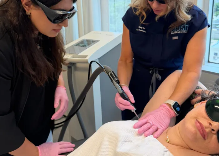 Two instructors treating a client's underarm during a Corpus Christi laser hair removal hands-on training workshop.
