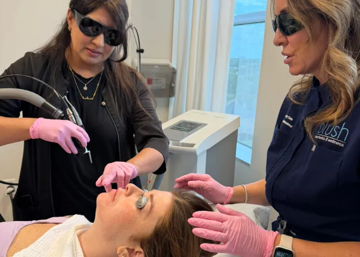 Instructors performing clinical facial treatment on a patient during Houston laser hair removal hands-on training.